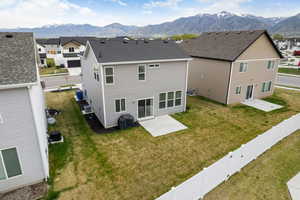 Rear view of house with a lawn, a fenced backyard, a mountain view, and a patio