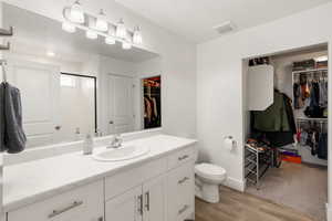 Full bathroom featuring wood finished floors, a stall shower, vanity, toilet, and visible vents