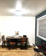 Dining area featuring wood finished floors, a textured ceiling, and baseboards