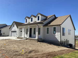 Cape cod home with central AC unit, concrete driveway, a shingled roof, a porch, and a garage