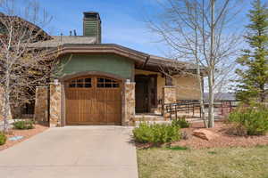 Ranch-style house with a chimney, a garage, concrete driveway, and stone siding
