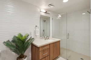 Full bath featuring visible vents, a stall shower, and vanity