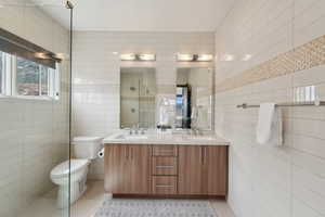 Full bathroom with tile walls, a stall shower, tile patterned floors, and a sink