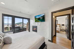 Bedroom with a fireplace, visible vents, light wood finished floors, and baseboards