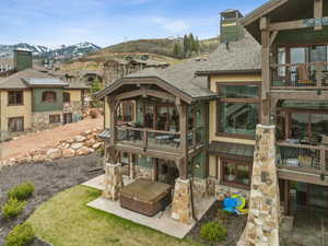 Back of house featuring a chimney, stone siding, a mountain view, a patio area, and a balcony
