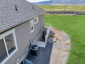View of side of property featuring a mountain view, roof with shingles, and fence