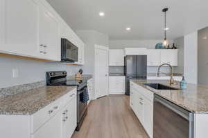 Kitchen with white cabinets, light wood-style floors, appliances with stainless steel finishes, and a sink