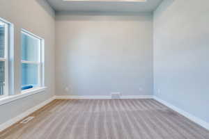 Carpeted empty room with visible vents and baseboards