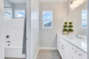 Full bathroom with baseboards, shower / bath combo with shower curtain, and vanity