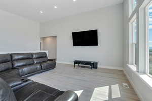 Living area with light wood-style floors, recessed lighting, visible vents, and baseboards
