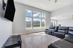Living area featuring wood finished floors, recessed lighting, baseboards, and ceiling fan with notable chandelier