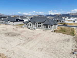 Back of house with a shingled roof, a mountain view, and a residential view