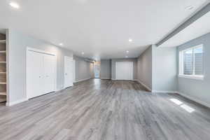 Unfurnished living room featuring light wood-type flooring, recessed lighting, and baseboards