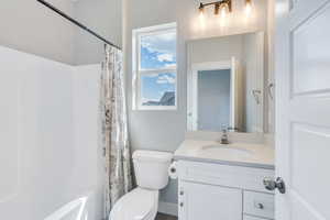 Full bathroom featuring toilet, shower / bath combo with shower curtain, and vanity