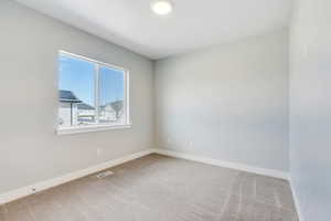 Carpeted empty room with visible vents and baseboards