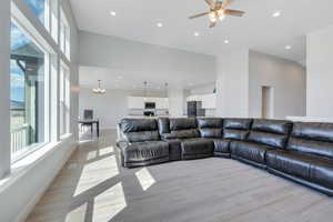 Living area featuring recessed lighting, light wood finished floors, baseboards, and ceiling fan with notable chandelier