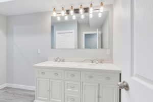 Bathroom featuring double vanity, a sink, visible vents, and baseboards