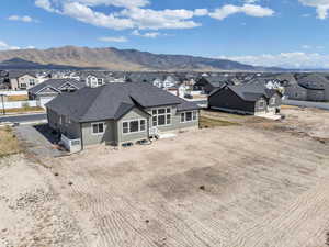 Back of property with stucco siding, roof with shingles, a mountain view, and a residential view
