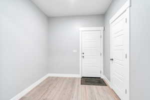 Doorway to outside with light wood-type flooring and baseboards