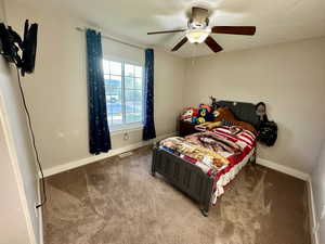Carpeted bedroom with visible vents, a ceiling fan, and baseboards