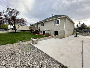 Back of property featuring a deck, fence, a yard, and a patio area