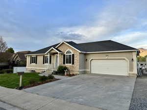 Ranch-style home featuring stucco siding, stone siding, a front lawn, concrete driveway, and an attached garage
