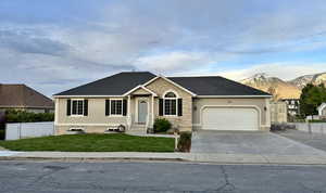 Ranch-style home with a front yard, a garage, a mountain view, stucco siding, and fence