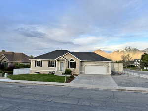 Single story home featuring fence, driveway, a mountain view, a front lawn, and an attached garage