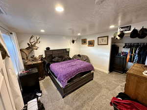 Carpeted bedroom with a textured ceiling, recessed lighting, and baseboards