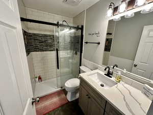 Full bath with toilet, visible vents, a shower stall, and vanity