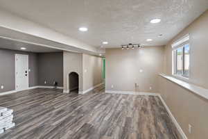 Basement with a textured ceiling, visible vents, wood finished floors, and baseboards