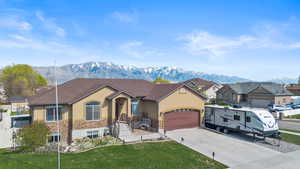 View of front of property featuring driveway, stone siding, a mountain view, stucco siding, and a garage