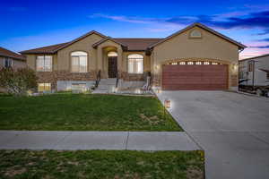 Ranch-style home with stucco siding, stone siding, a front lawn, concrete driveway, and an attached garage