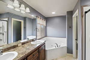 Bathroom with a whirlpool tub, a sink, and tile patterned floors