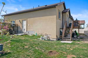 Back of house featuring fence, a wooden deck, stucco siding, stairway, and a yard
