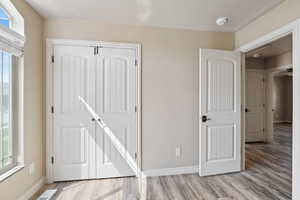 Unfurnished bedroom with multiple windows, wood finished floors, and baseboards
