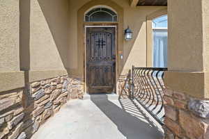 Doorway to property with stone siding and stucco siding