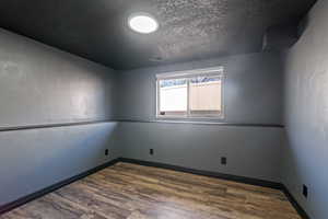 Empty room with baseboards, visible vents, wood finished floors, and a textured ceiling