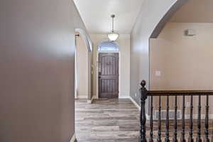 Entryway with wood finished floors, baseboards, visible vents, and arched walkways