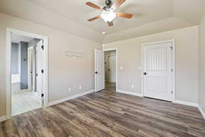 Unfurnished bedroom with wood finished floors, ensuite bathroom, and baseboards