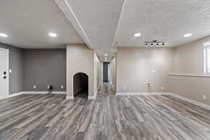 Basement with baseboards, recessed lighting, wood finished floors, and a textured ceiling