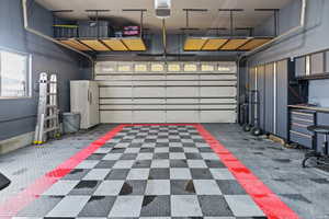 Garage featuring a garage door opener and freestanding refrigerator