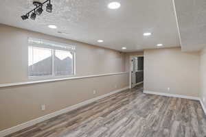 Below grade area featuring baseboards, recessed lighting, wood finished floors, and a textured ceiling