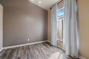 Unfurnished room featuring visible vents, wood finished floors, and baseboards