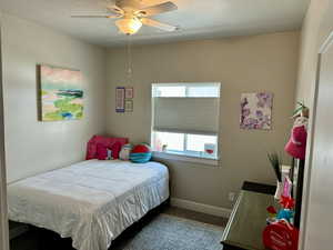 Carpeted bedroom featuring a ceiling fan, baseboards, and a textured ceiling
