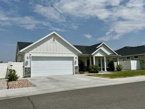 View of front of property with board and batten siding, fence, stone siding, and a garage