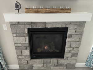 Room details with baseboards, a lit fireplace, and wood finished floors