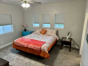Carpeted bedroom with visible vents, a ceiling fan, baseboards, and multiple windows