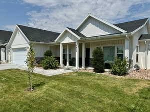 View of front of property featuring concrete driveway, an attached garage, a shingled roof, board and batten siding, and a front yard