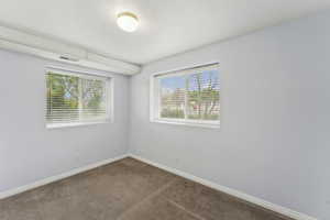 Spare room featuring dark carpet, baseboards, and visible vents